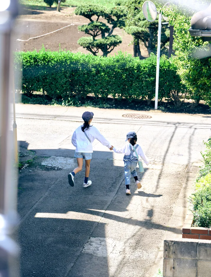 写真:子供たちが手をつないで外遊びに行く後ろ姿