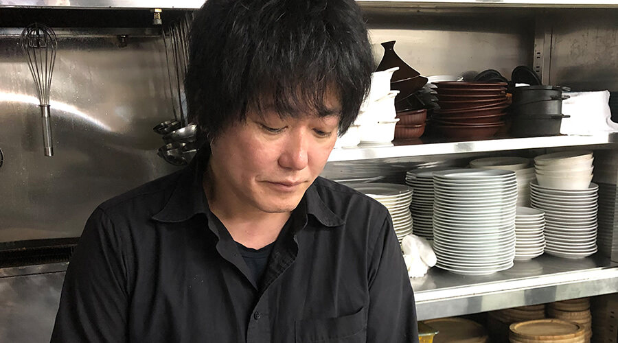 厨房で作業中の稲田俊輔氏