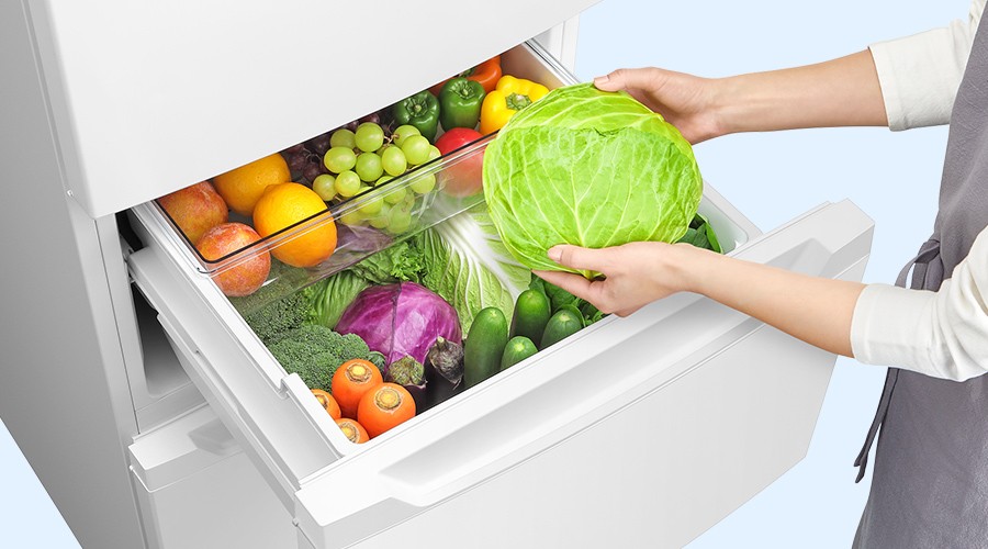 真ん中レイアウトの野菜室からキャベツを取り出す人