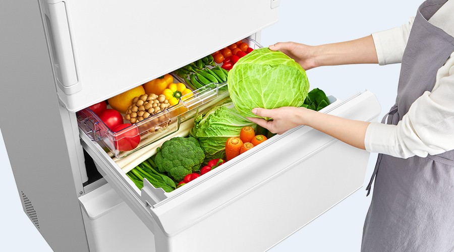 真ん中レイアウトの野菜室からキャベツを取り出す人