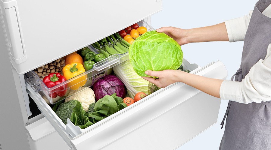 真ん中レイアウトの野菜室からキャベツを取り出す人